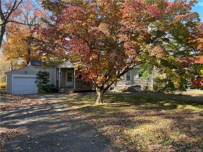 View of property hidden behind natural elements featuring a porch, a front lawn, and a garage | Image 2