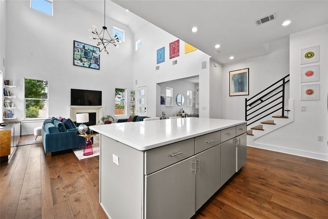 Kitchen with gray cabinets, a towering ceiling, dark wood finished floors, a kitchen island, and light countertops | Image 10