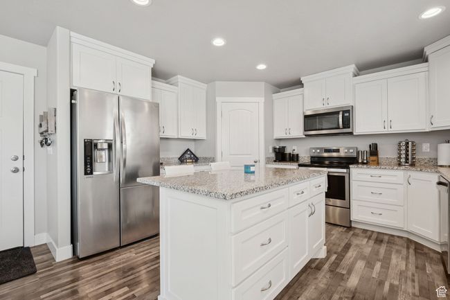 Kitchen featuring stainless steel appliances, dark wood finished floors, a kitchen island, recessed lighting, and white cabinets | Image 10