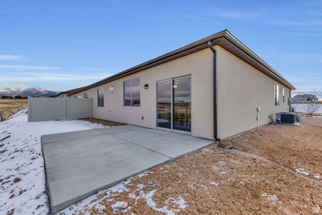 Snow covered back of property featuring a mountain view, central air condition unit, and a patio | Image 30