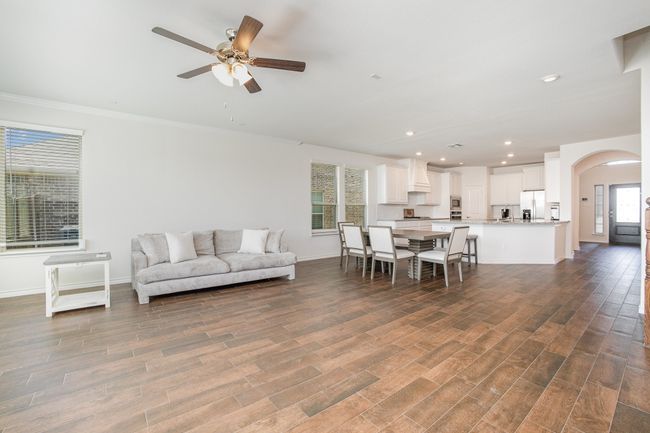 Living area with dark wood-style flooring, baseboards, ornamental molding, ceiling fan, and arched walkways | Image 6