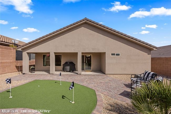 Rear view of house with a putting area, a patio, stucco siding, and fence | Image 59
