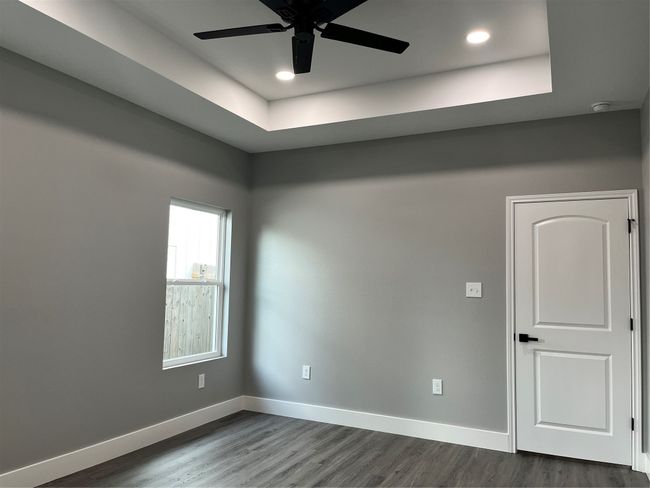 Spare room featuring a ceiling fan, dark wood finished floors, a smoke detector, recessed lighting, and a tray ceiling | Image 23