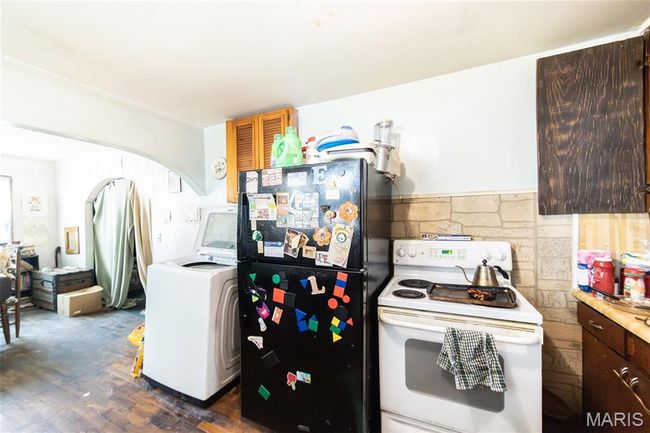 Kitchen featuring white range with electric cooktop, freestanding refrigerator, washer / dryer, dark wood-type flooring, and arched walkways | Image 10