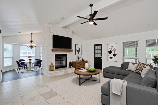 Living room with light tile patterned floors, a chandelier, ceiling fan, and a large fireplace | Image 5