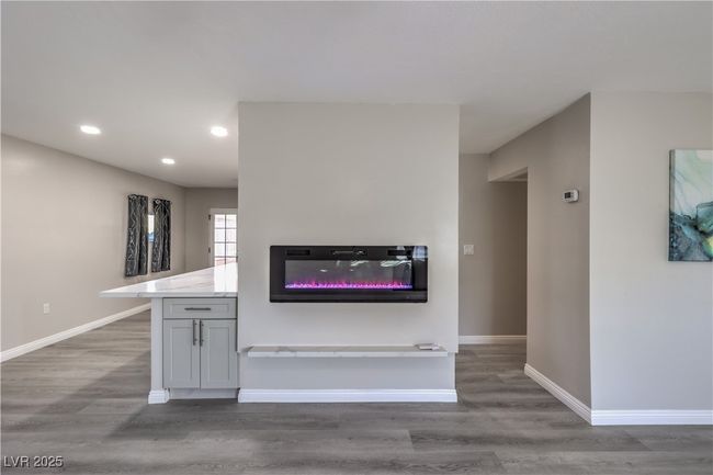 Kitchen with a glass covered fireplace, recessed lighting, wood finished floors, and baseboards | Image 10
