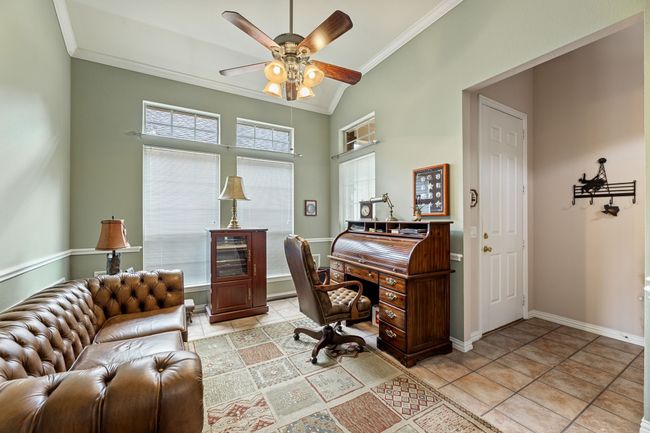 Office area featuring crown molding, a ceiling fan, baseboards, light tile patterned flooring, and vaulted ceiling | Image 9