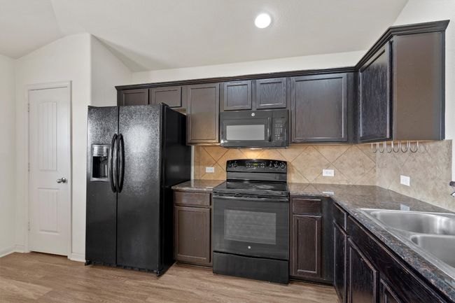 Granite and backsplash tie together the light flooring and dark cabinetry for a warm, coordinated​​‌​​​​‌​​‌‌​‌‌​​​‌‌​​‌‌​‌​​​​​‌ finish. | Image 7