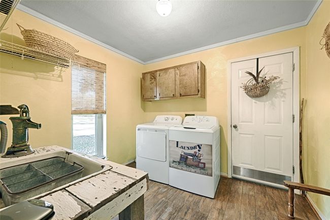 Laundry room with cabinets, dark hardwood / wood-style flooring, separate washer and dryer, and crown molding | Image 34