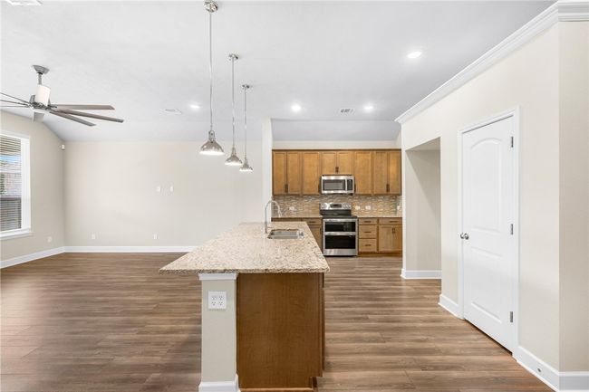 Kitchen with appliances with stainless steel finishes, a sink, a ceiling fan, dark wood-style floors, and brown cabinetry | Image 14