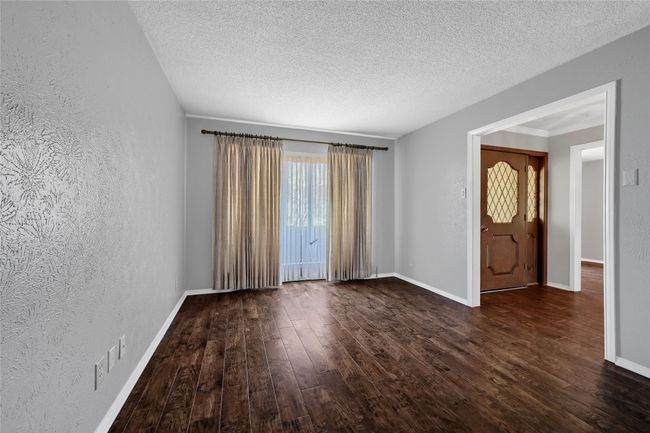 Unfurnished room featuring a textured ceiling, a textured wall, baseboards, and dark wood finished floors | Image 6