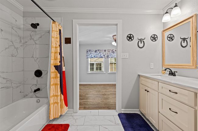 Full bathroom with shower / bath combo, marble finish floor, vanity, and crown molding | Image 16
