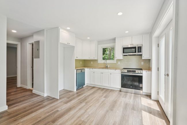 Featuring white cabinetry, stainless steel finishes, light wood-style floors, neutral backsplash, recessed lighting | Image 5