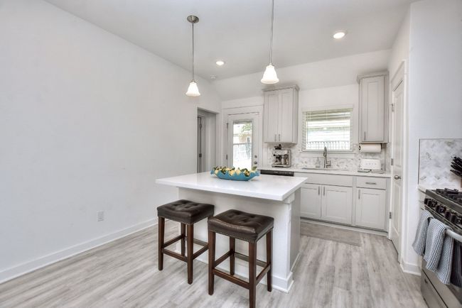 Kitchen with a kitchen breakfast bar, range, light countertops, backsplash, and a sink | Image 14