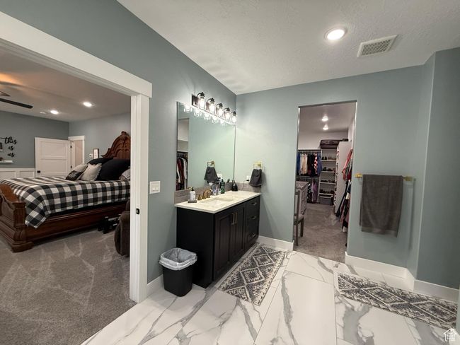 Bathroom with vanity, a spacious closet, baseboards, a textured ceiling, and visible vents | Image 38