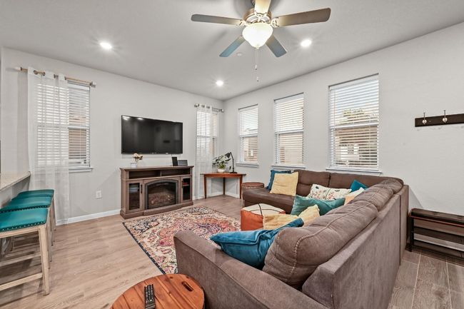 Several windows surround the cozy living space, filling the room with natural light and creating an airy, welcoming atmosphere | Image 7
