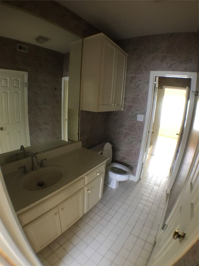 Bathroom featuring tile patterned floors, wallpapered walls, vanity, toilet, and visible vents | Image 5