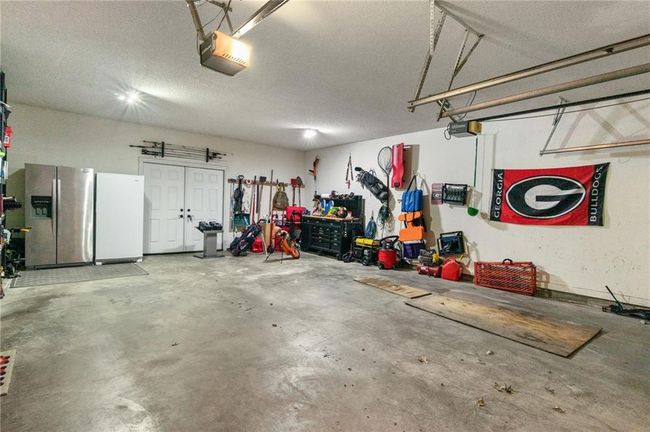 Garage with stainless steel refrigerator with ice dispenser, a garage door opener, and white refrigerator | Image 49