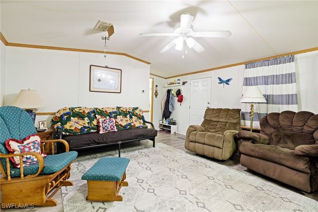 Living area featuring crown molding, lofted ceiling, ceiling fan, and new luxury vinyl flooring | Image 4