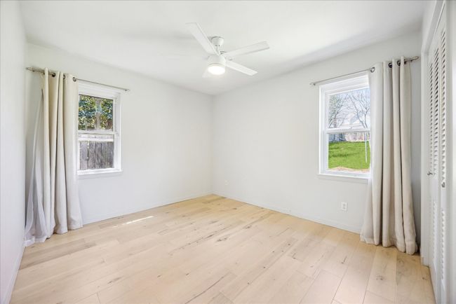 Empty room with light wood-style flooring, baseboards, a healthy amount of sunlight, and ceiling fan | Image 18