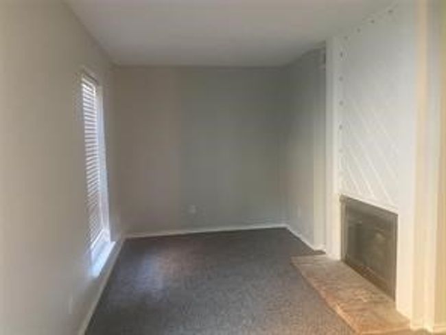 Unfurnished living room featuring a glass covered fireplace and dark colored carpet | Image 15