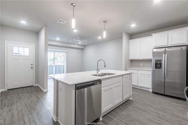 Kitchen featuring hanging light fixtures, stainless steel appliances, white cabinets, ceiling fan, and sink | Image 5