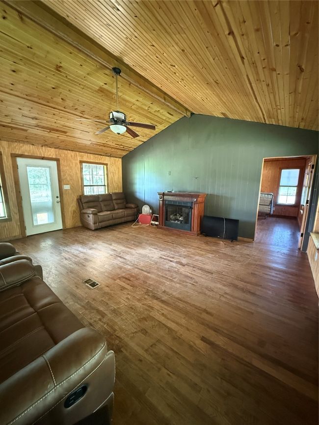 Living room featuring hardwood / wood-style flooring, a ceiling fan, a fireplace, and wood walls | Image 18