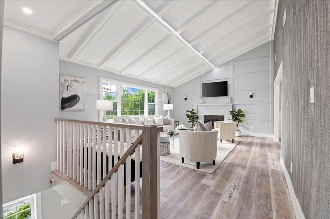 Living area featuring light wood finished floors, lofted ceiling, and a fireplace | Image 20