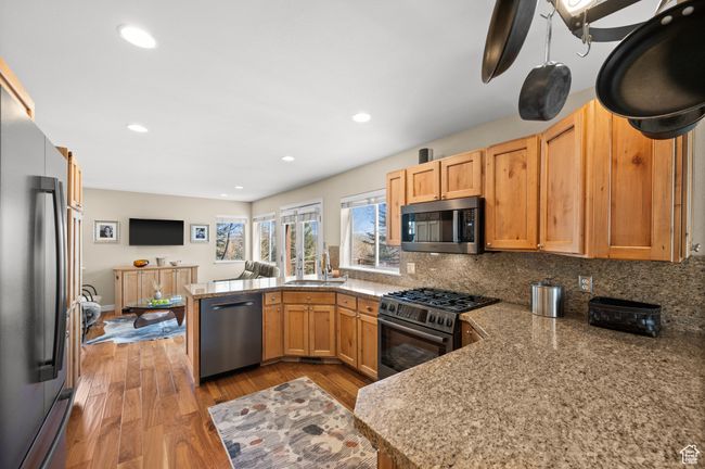 Kitchen with a peninsula, wood finished floors, decorative backsplash, and stainless steel appliances | Image 10