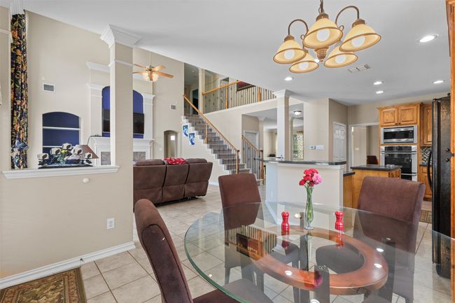 Dining room with ornate columns, ceiling fan, a chandelier, light tile patterned floors, and baseboards | Image 12