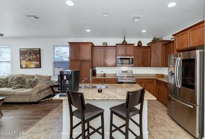 This modern kitchen showcases a stunning island topped with luxurious granite, offering both style and functionality. The sleek stainless steel appliances add a contemporary touch, perfectly complementing the warm cabinetry and inviting atmosphere. | Image 3