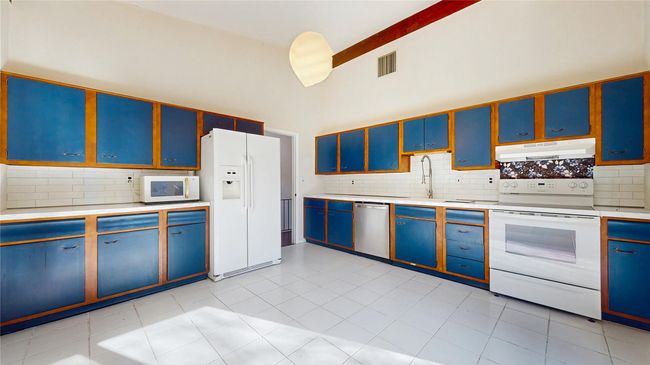Kitchen featuring white appliances, visible vents, light countertops, under cabinet range hood, and blue cabinets | Image 10
