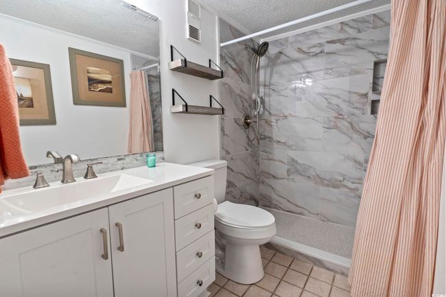 Full bath with vanity, toilet, a textured ceiling, visible vents, and tiled shower | Image 9
