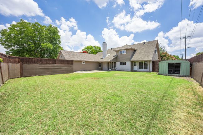 Rear view of property with a storage shed, a fenced backyard, a patio area, a chimney, and roof with shingles | Image 18