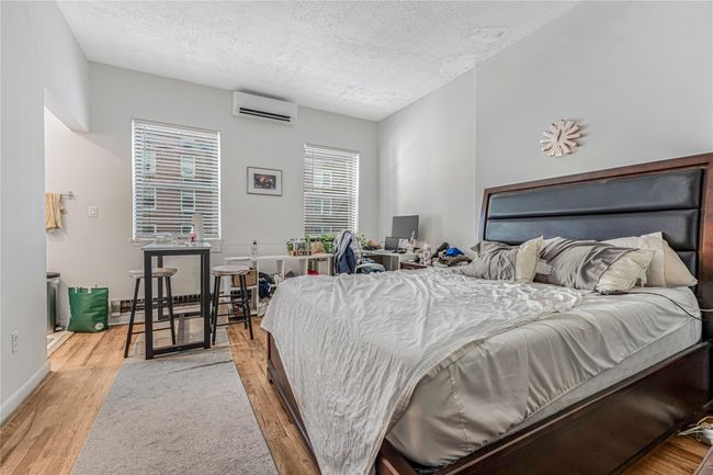 Bedroom with a wall mounted air conditioner, a textured ceiling, and wood finished floors | Image 21