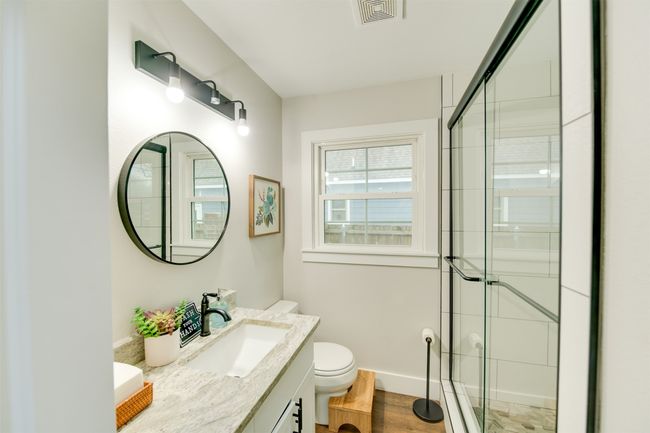 Bathroom with baseboards, visible vents, toilet, a tile shower, and vanity | Image 17