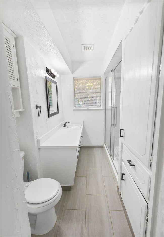 Bathroom featuring a shower with door, vanity, a textured ceiling, and toilet | Image 8