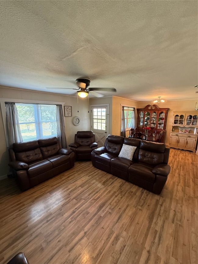 Living area with a textured ceiling, wood finished floors, and ceiling fan | Image 10