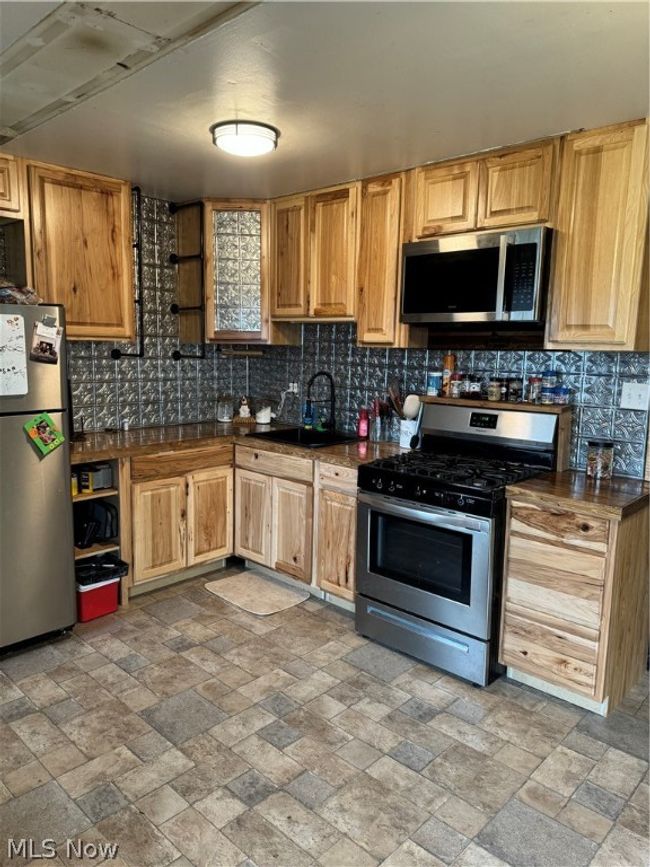 Kitchen featuring tasteful backsplash, sink, range, light tile floors, and fridge | Image 3