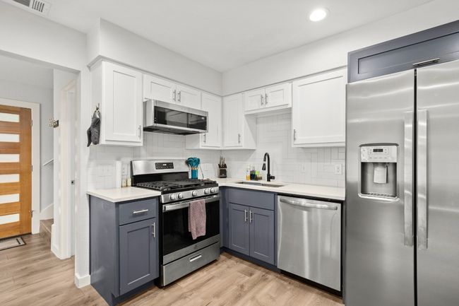 Kitchen with appliances with stainless steel finishes, light countertops, white cabinets, tasteful backsplash, and recessed lighting | Image 15