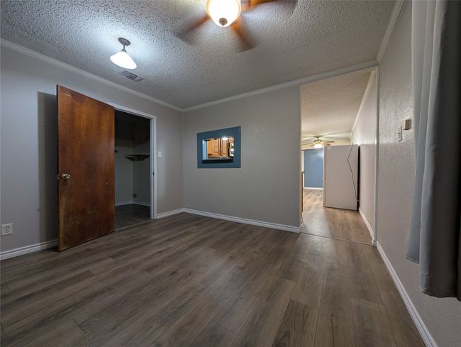 Unfurnished bedroom featuring wood finished floors, a textured ceiling, crown molding, and visible vents | Image 10