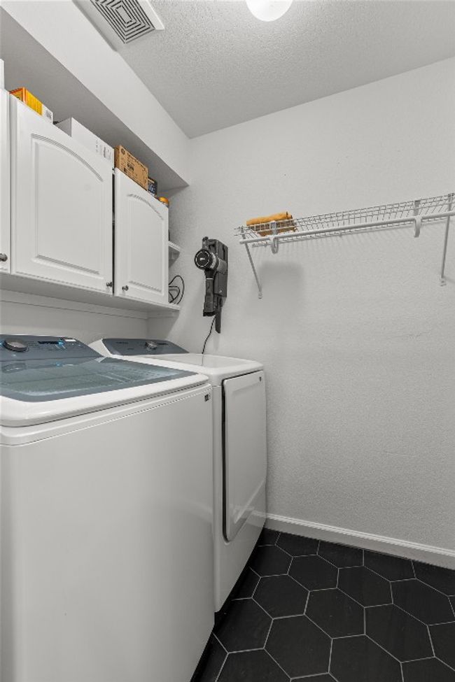 Laundry area with separate washer and dryer, cabinet space, and dark tile patterned flooring | Image 26