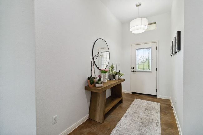 Entryway featuring concrete floors, baseboards, and a towering ceiling | Image 4
