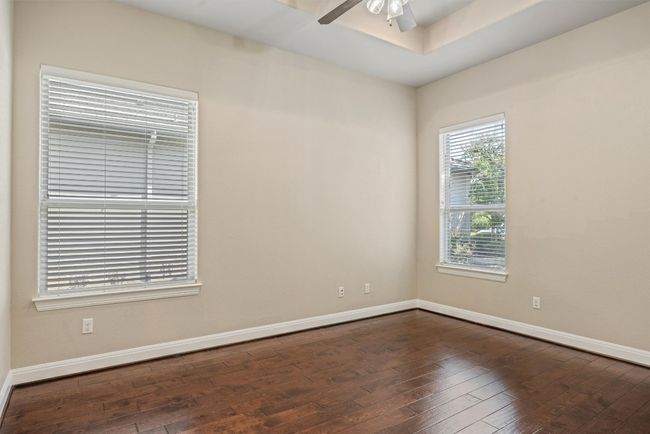 French doors lead to a dedicated office or bedroom with engineered wood flooring and ceiling fan | Image 26
