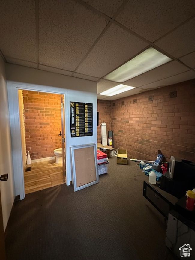 Interior space featuring a drop ceiling, carpet flooring, and brick wall | Image 11