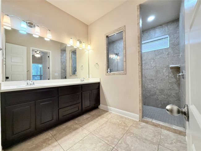 Bathroom with double vanity, walk in shower, tile patterned floors, and a ceiling fan | Image 30