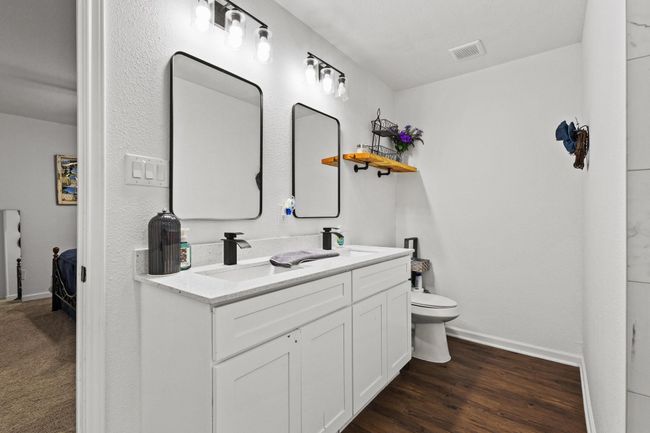 Ensuite bathroom featuring baseboards, toilet, double vanity, and wood finished floors | Image 13