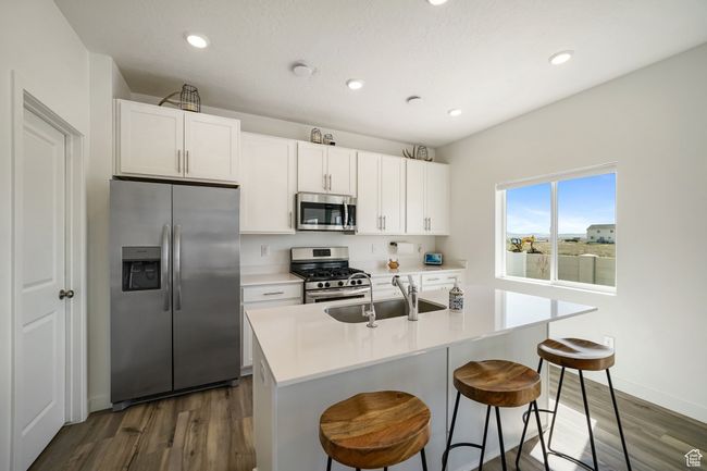 Kitchen with appliances with stainless steel finishes, a sink, dark wood-style floors, recessed lighting, and white cabinets | Image 15
