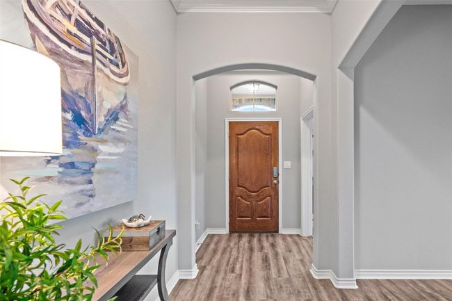 Foyer with arched walkways, wood finished floors, ornamental molding, and baseboards | Image 4
