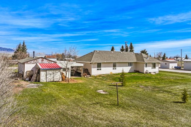 Back of property with an outdoor structure, a storage shed, roof with shingles, stairway, and a yard | Image 10